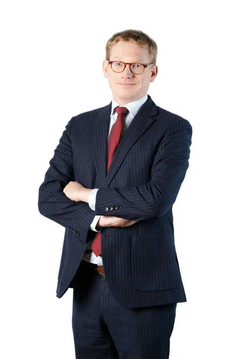Retrato corporativo de un hombre con traje azul y corbata roja.