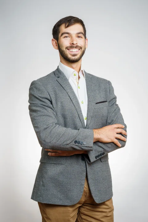Retrato corporativo de un hombre con traje gris y brazos cruzados.