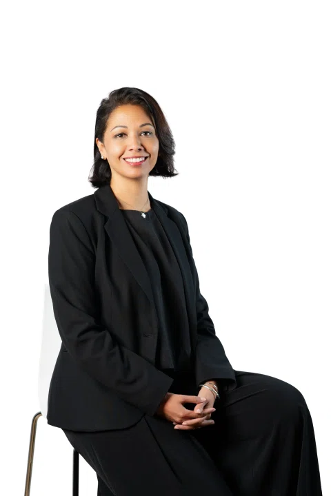 Retrato corporativo de una mujer con traje negro sentada.