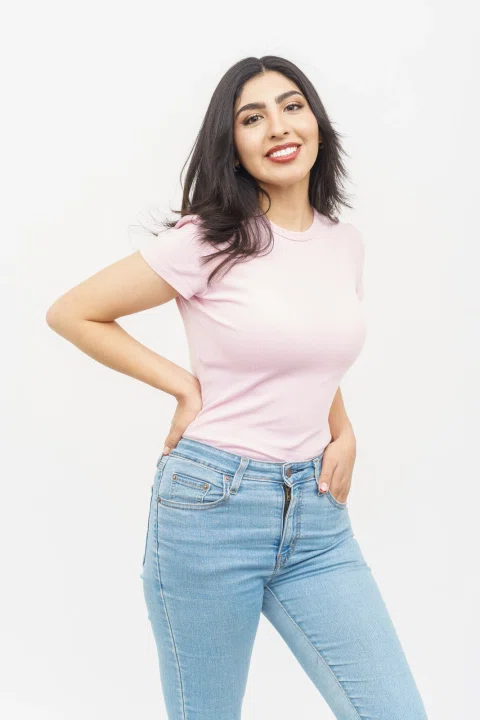 Retrato de estudio de una modelo con camiseta rosada y jeans.