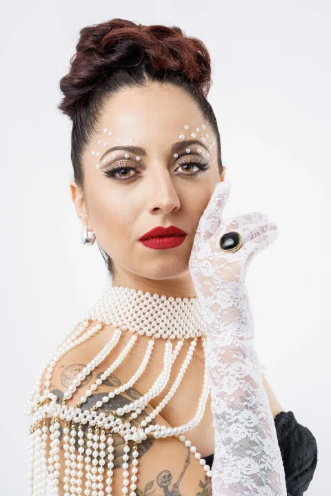 Retrato editorial de una mujer con guantes y accesorios de perlas.