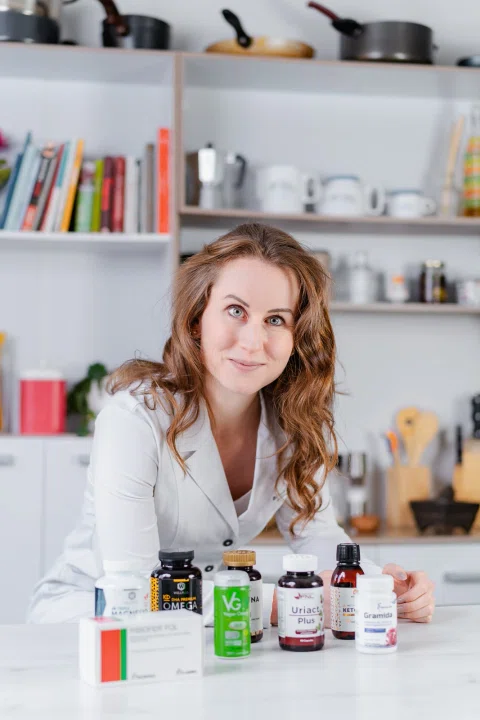 Retrato de una mujer en su entorno de trabajo junto a productos farmacéuticos.