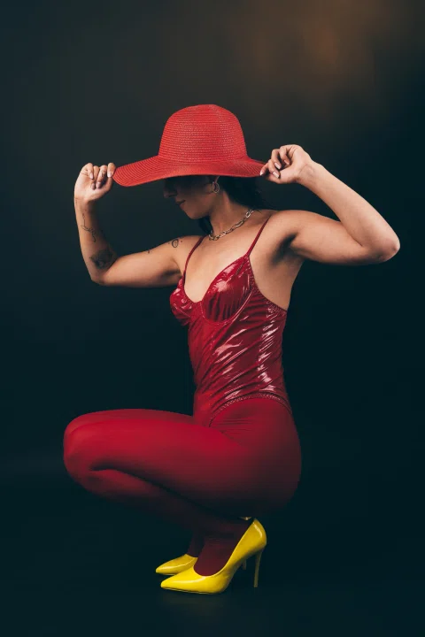Retrato editorial de una mujer con vestido rojo y sombrero.