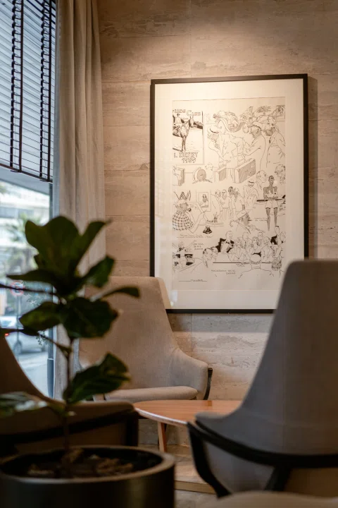 Rincón de lobby de hotel con sillón, planta y obra mural.