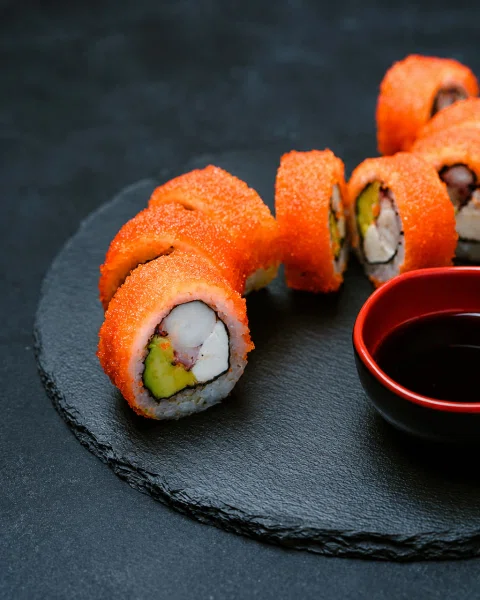 Roll de sushi cubierto de salmón con salsa de soya.