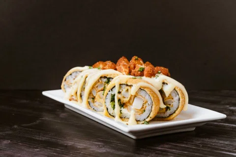 Rolls fritos con salsa cremosa en plato blanco.