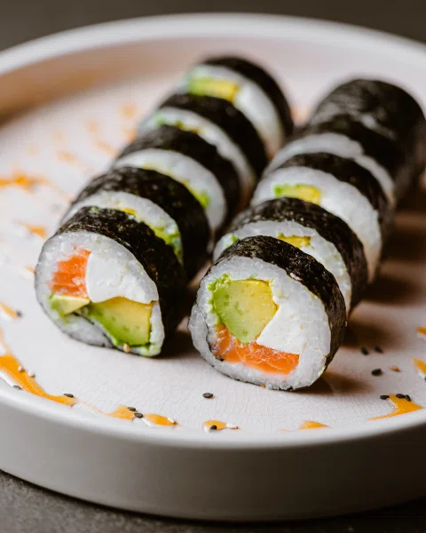 Rolls de sushi envueltos en nori sobre plato blanco.