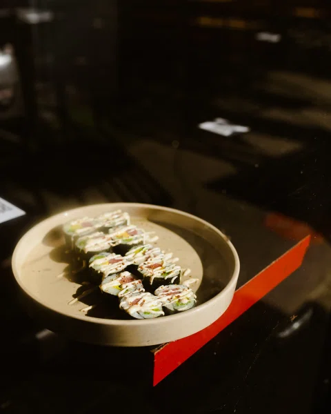 Rolls de sushi sobre plato en ambiente oscuro.