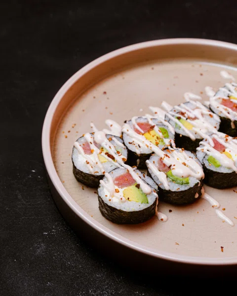 Rolls de sushi servidos en plato de cerámica.
