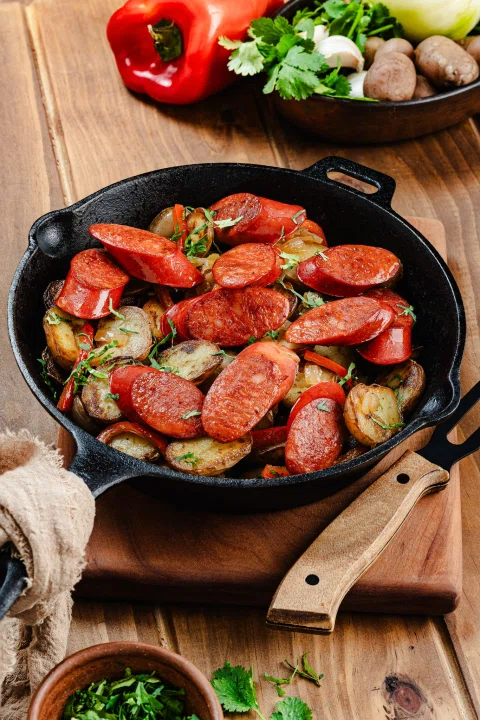 Salchichas vegetales asadas con pimientos en sartén.