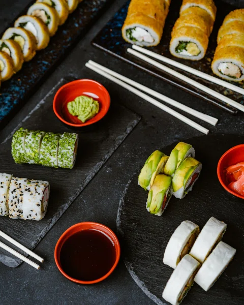 Selección de sushi salsas y rolls sobre mesa oscura.