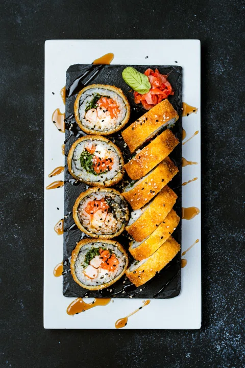 Rolls de sushi presentados en una bandeja y fotografiados desde arriba.