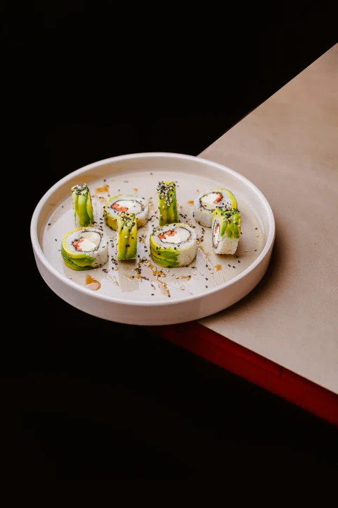 Rolls de sushi servidos en un plato claro sobre una mesa de diseño.
