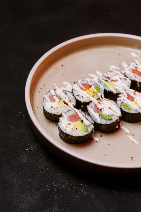 Rolls de sushi servidos en un plato rosado.