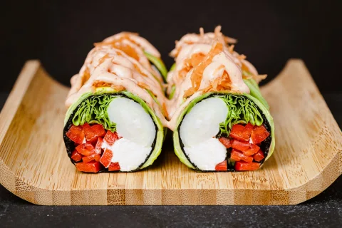 Rolls de sushi con vegetales presentados en una bandeja de madera.
