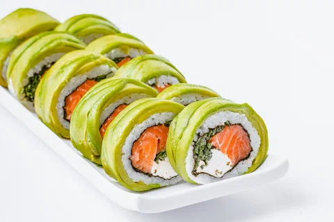 Roll de sushi con salmón y palta presentado sobre un plato blanco.