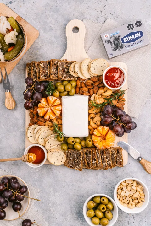 Tabla de aperitivo con queso frutos secos y aceitunas.