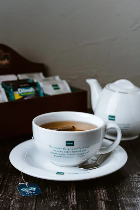 Taza de té servida junto a una tetera y sobres de infusión.
