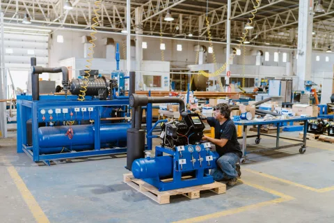 Técnico trabaja con maquinaria dentro de una planta industrial.