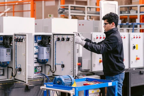 Técnico trabaja con tableros eléctricos dentro de una planta industrial.