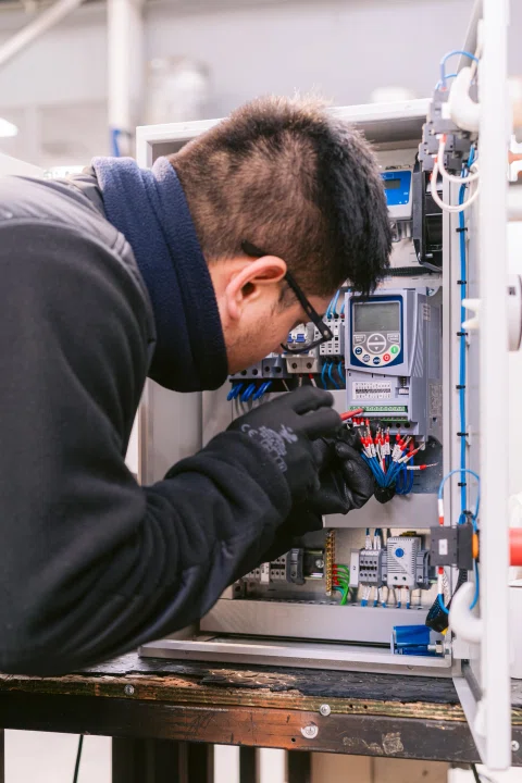 Técnico trabajando dentro de gabinete eléctrico abierto.
