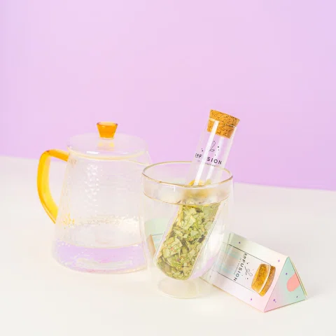Tetera transparente con tubo de infusión y hierbas.