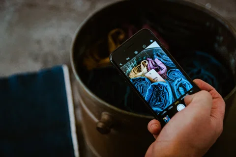 Persona fotografía textiles de colores con un teléfono móvil.