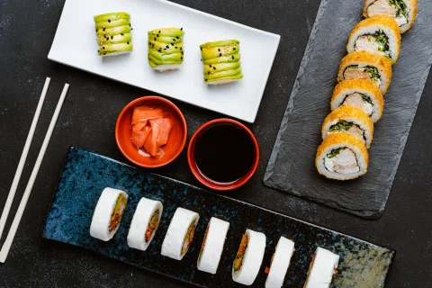 Varios tipos de rolls de sushi dispuestos con salsas.