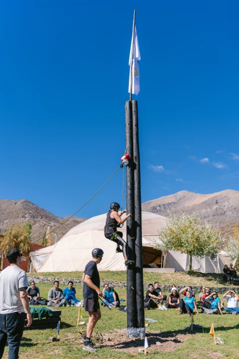 Participante asciende una torre durante una actividad de equipo.