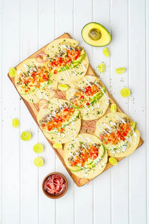 Tostadas con vegetales y palta sobre tabla.