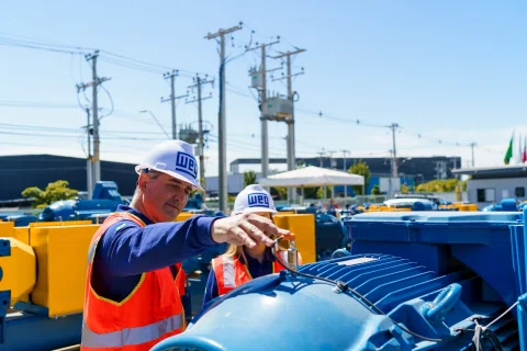 Trabajador ajustando componente sobre motor industrial azul.