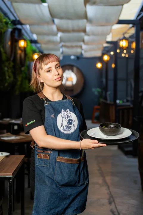 Trabajadora del restaurante sosteniendo un plato.