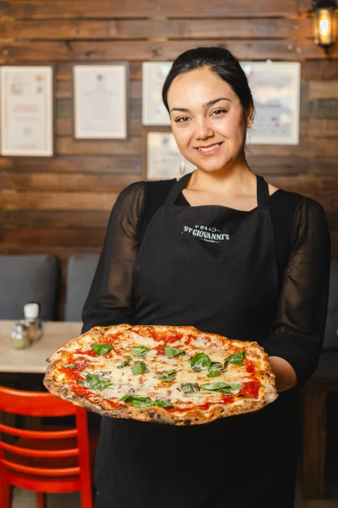Trabajadora de St Giovanni's sosteniendo pizza.