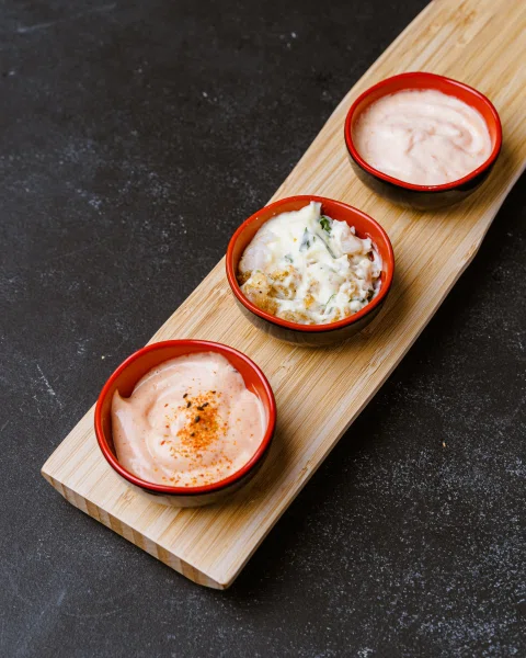 Tres salsas servidas en recipientes sobre tabla.