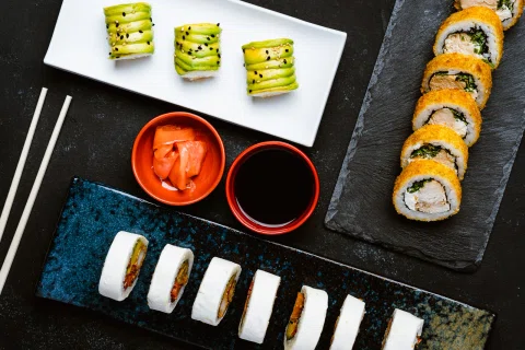 Variedad de sushi presentada con distintas salsas.