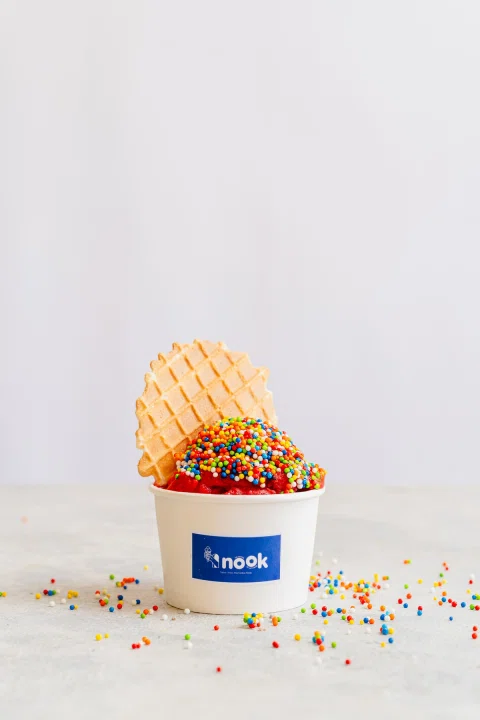 Vaso azul de helado Nook con cono waffle y sprinkles.