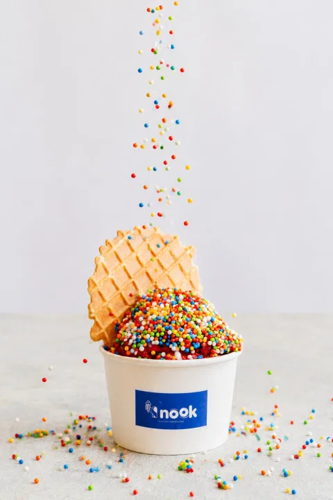 Helado Nook con cono y sprinkles en una composición de producto.