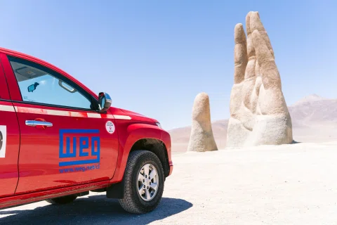 Vehículo WEG frente a escultura Mano del Desierto.