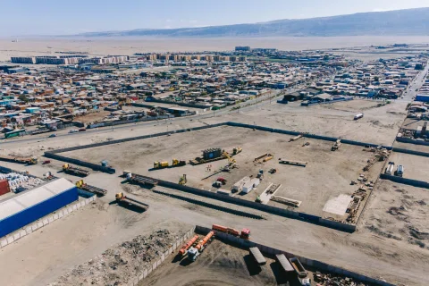 Vista aérea de una faena industrial con maquinaria y zona urbana al fondo.